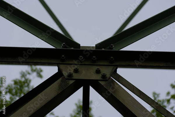 Fototapeta An imposing metal structure's bolted connections highlight industrial strength and precision against a stark sky, showcasing engineering detail