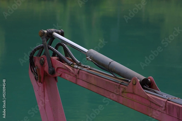 Fototapeta A robust hydraulic arm in bold red and silver stands against a calming teal backdrop, showcasing industrial power and precision