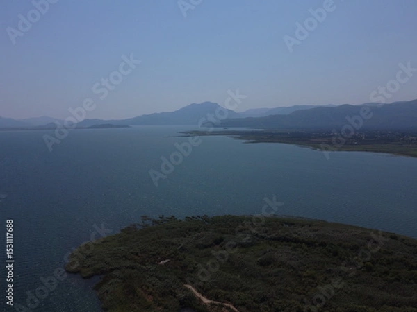 Fototapeta A serene aerial view of Lake Köyceğiz in Turkey on a calm summer day, showcasing tranquil blue waters, lush surroundings, and peaceful natural beauty.