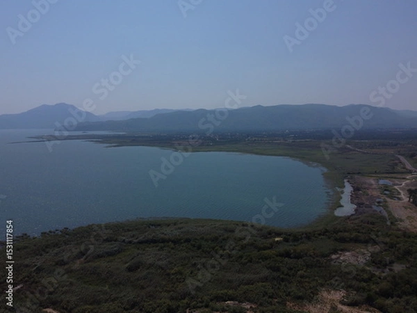 Fototapeta A serene aerial view of Lake Köyceğiz in Turkey on a calm summer day, showcasing tranquil blue waters, lush surroundings, and peaceful natural beauty.