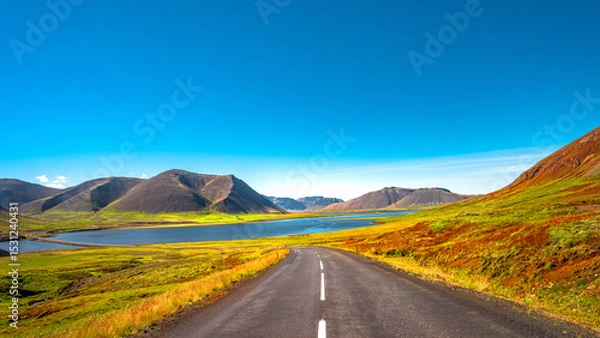 Fototapeta Panorama with a paved road, Ring road, through rough and colorful Icelandic landscape, Iceland, summer, suny blue sky