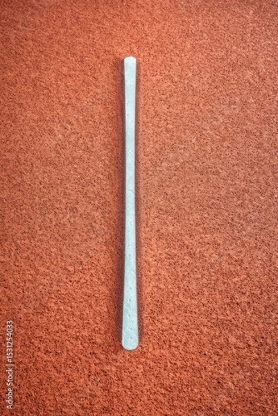 Fototapeta White Vertical Stick on Red Running Track Surface