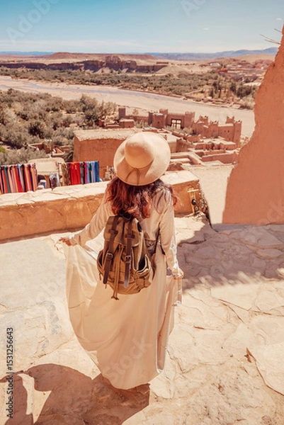 Fototapeta Tourist with backpack and hat walking in Ait Benhaddou, Morocco, admiring the landscape