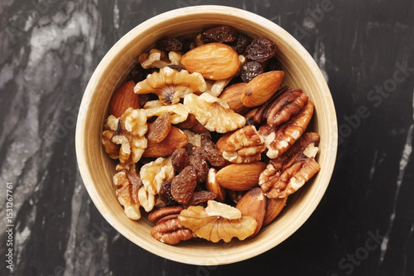 Fototapeta Mixed nuts in wooden bowl. Walnuts almonds pecans and raisins. Natural healthy snack full of energy. Close-up on marble table. Rustic style. Ideal for diet plans and clean eating habits.