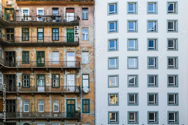 Fototapeta A contrast between two houses. The old and the new one. The old house can be seen in the reflection in the glass. 