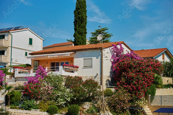 Obraz White Mediterranean house with large balcony and blooming garden. White villa with flowers near Adriatic coast. Coastal architecture in Croatia