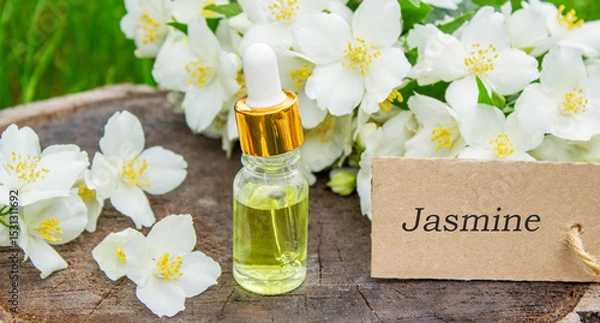 Fototapeta Jasmine essential oil in a glass bottle and jasmine flowers. Oils.