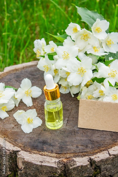 Fototapeta Jasmine essential oil in a glass bottle and jasmine flowers. Oils.