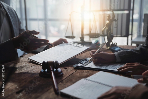 Fototapeta Lawyers working together on a legal document, reviewing and signing agreements in a courtroom setting, with a gavel and scales of justice in the background