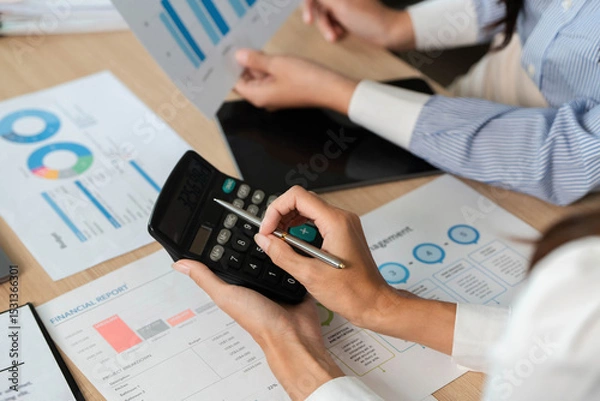 Obraz Calculating Financial Metrics. Professionals using a calculator for financial analysis and reports.