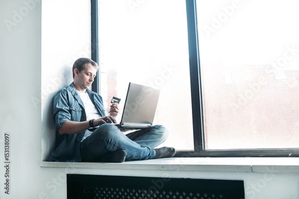 Fototapeta handsome hipster modern man manager paying by credit card internet using laptop at home