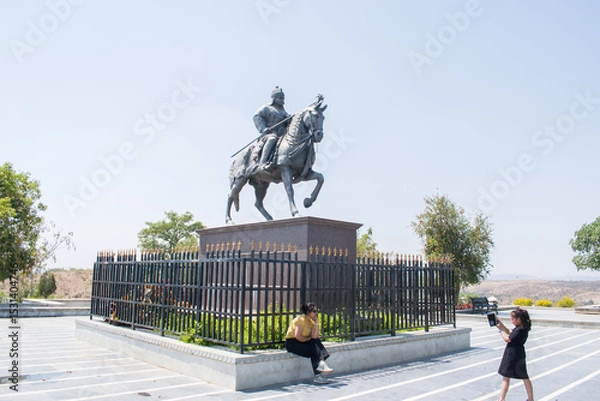 Obraz a young mother posing joyfully while her little daughter captures the moment on a mobile phone, on backdrop of the Maharana Pratap statue in Haldighati, Rajasthan. essence of travel, heritage, bonding