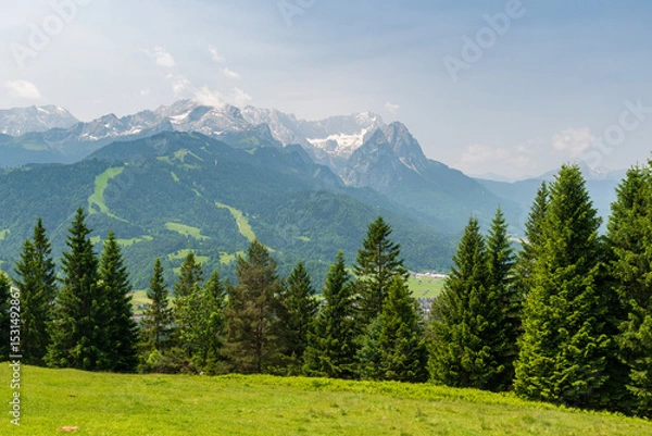 Fototapeta Hiking above the clouds on Wankberg, Germany—panoramic views of snow-capped Alps and lush valleys under a bright blue sky.