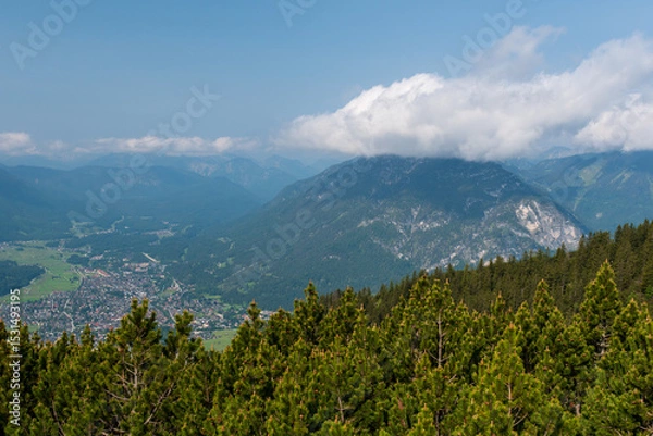 Fototapeta Hiking above the clouds on Wankberg, Germany—panoramic views of snow-capped Alps and lush valleys under a bright blue sky.