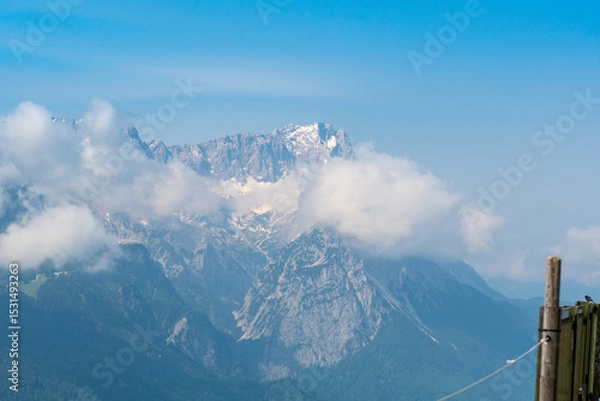 Fototapeta Hiking above the clouds on Wankberg, Germany—panoramic views of snow-capped Alps and lush valleys under a bright blue sky.