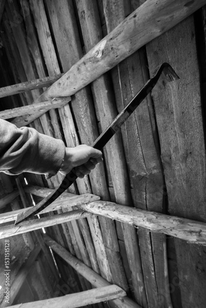 Obraz Person gripping a metal prying tool inside a weathered wooden structure