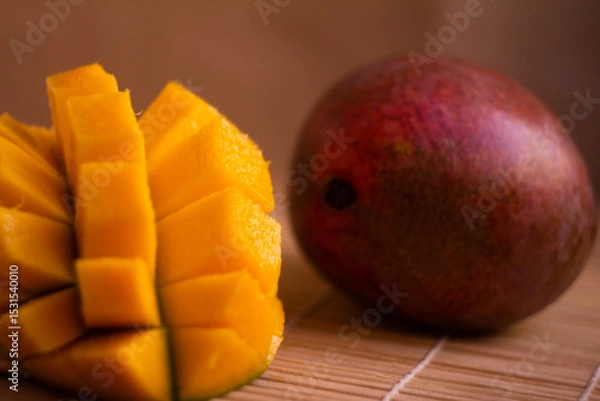 Fototapeta Close-Up of Fresh Mango Slices and a Whole Mango on Wooden Surface