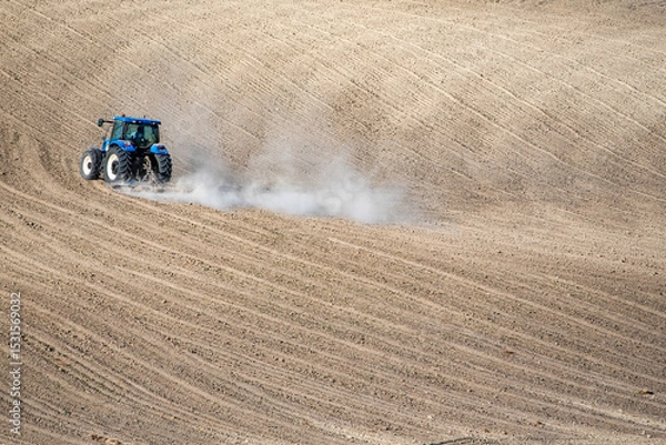 Fototapeta A tractor moves across freshly plowed wavy soil, highlighting agricultural machinery and rural productivity in a minimalist landscape