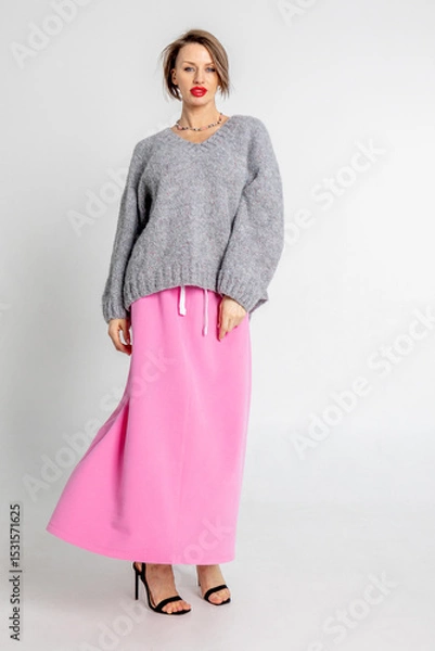 Obraz Beautiful girl of model appearance. Portrait of cheerful woman in gray jumper and pink skirt. Vertical photo. High quality photo