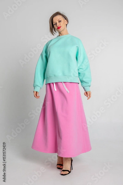 Obraz Beautiful girl of model appearance. Portrait of beautiful woman in mint color sweatshirt and pink skirt. Vertical photo. High quality photo