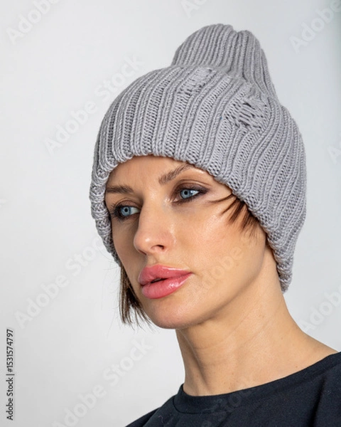 Obraz Portrait beautiful woman in grey hat. Pretty girl in warm clothes on grey background. Studio photography. Vertical photo