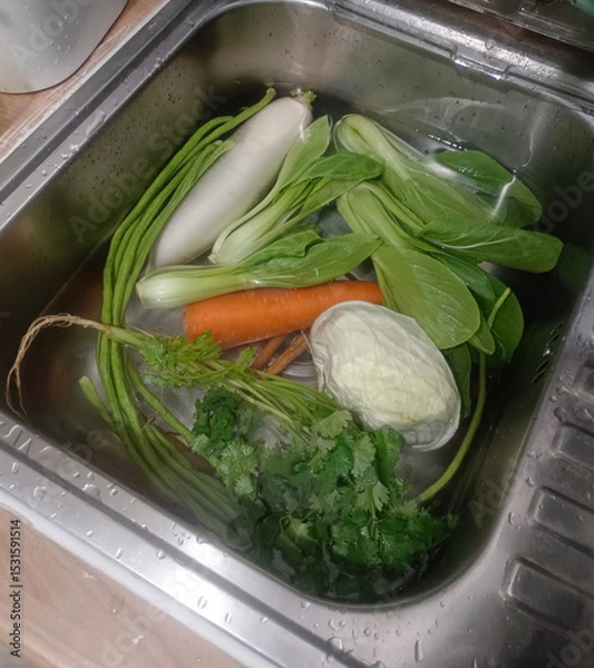 Fototapeta Top view Clean and soak vegetables,  coriander, carrots, Chinese kale, green beans, and cabbage in the sink on wooden background, protect, clean, fresh, copy space
