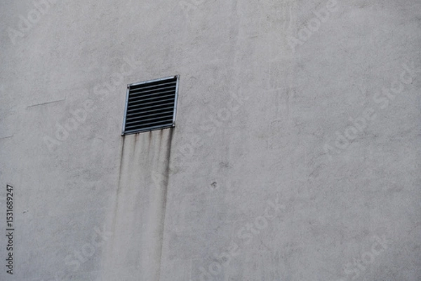 Fototapeta A ventilation shaft with a grille in front of it on a house wall