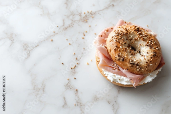 Fototapeta Toasted bagel topped with cream cheese and smoked ham, garnished with sesame seeds