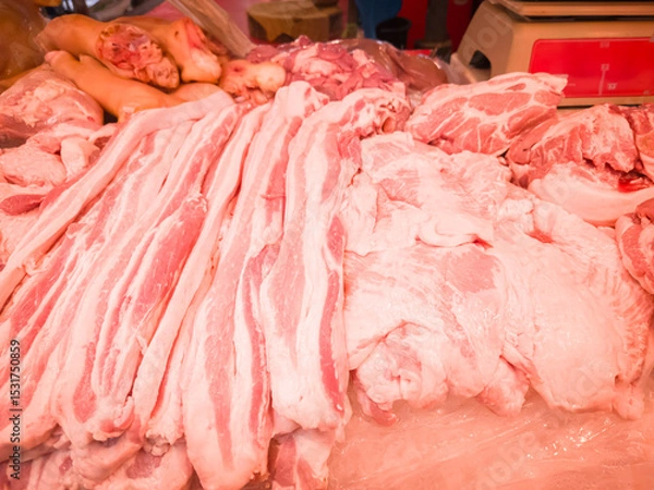 Obraz A vibrant market stall displaying various fresh pork cuts, including pork belly, shoulder, and pig trotters. 