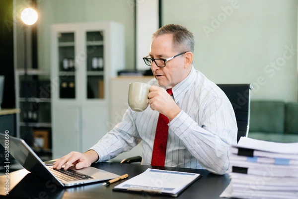Fototapeta Frustrated Mature Businessmann working on a laptop computer sitting at his working place