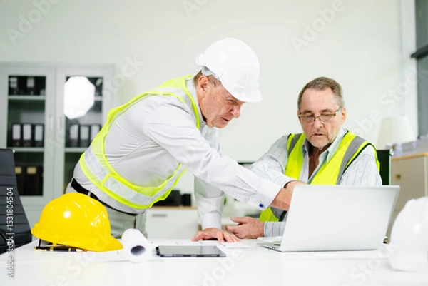Fototapeta Engineers planning a construction project with blueprints, tablets, and hardhats. Concept of teamwork, architecture