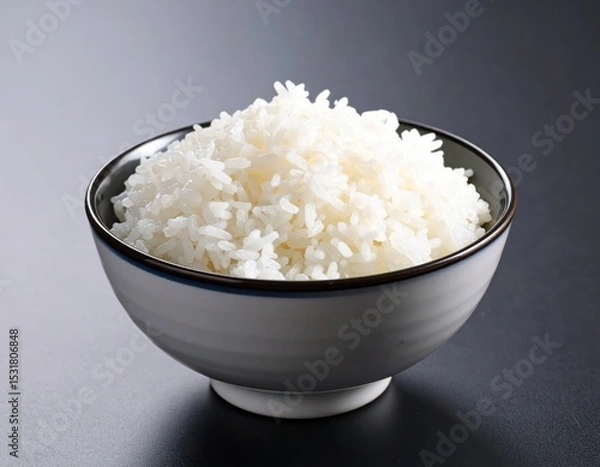Fototapeta Steaming hot fluffy white rice served in modern black and white bowl on dark surface