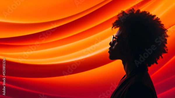 Obraz Profile view of a silhouette of an individual with curly hair and glasses, complemented by a vivid abstract orange backdrop, evoking modernity and thoughtful emotion.