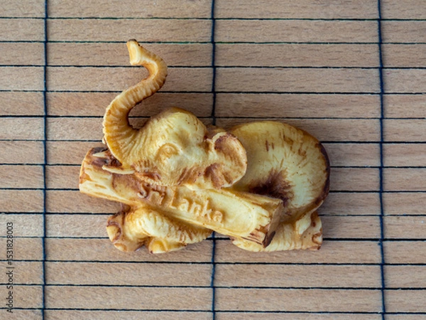 Obraz 
Fridge magnet with the symbol of Sri Lanka, the elephant. Souvenir from a trip on a wooden background. Exotic tropical country