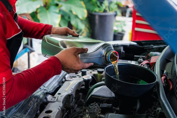 Fototapeta Car mechanic drain the old lubricant engine oil at car garage for changing the oil in a car engine