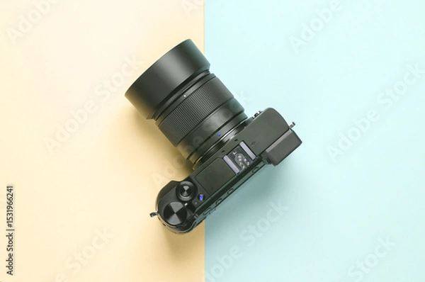 Fototapeta Modern digital mirrorless camera with a lens on a blue-yellow pastel background. Top view. Minimalism