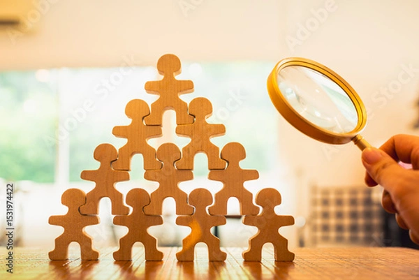 Fototapeta A magnifying glass and wooden figures with business hand search for someone who ‘s special person. Concept of Human resources management and recruitment.