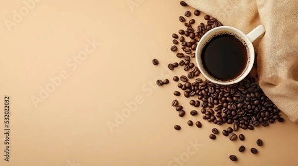 Fototapeta A cup of black coffee sits on a beige surface, surrounded by scattered coffee beans and a light brown cloth.