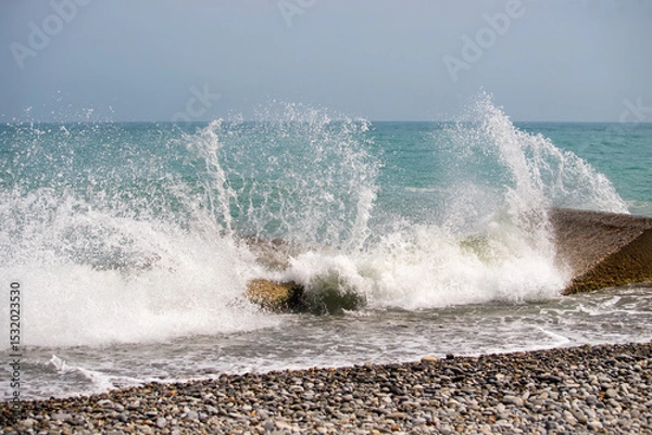 Fototapeta The ocean is crashing against the rocks, creating a powerful and dynamic scene