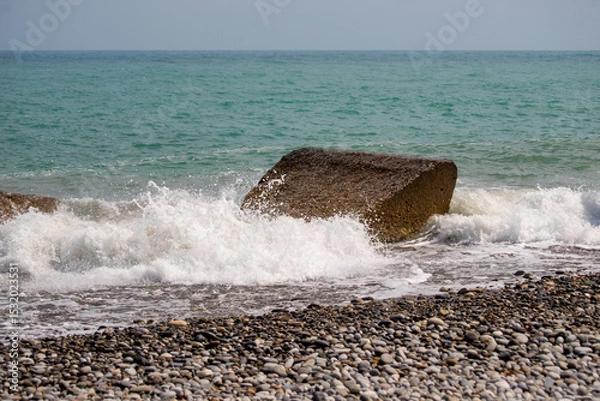 Fototapeta A large rock is in the ocean, and the water is crashing against it