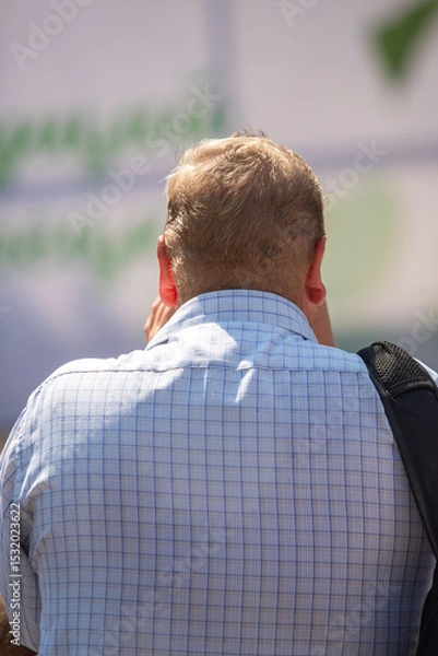 Fototapeta A man with a bald head is wearing a blue shirt with a plaid pattern