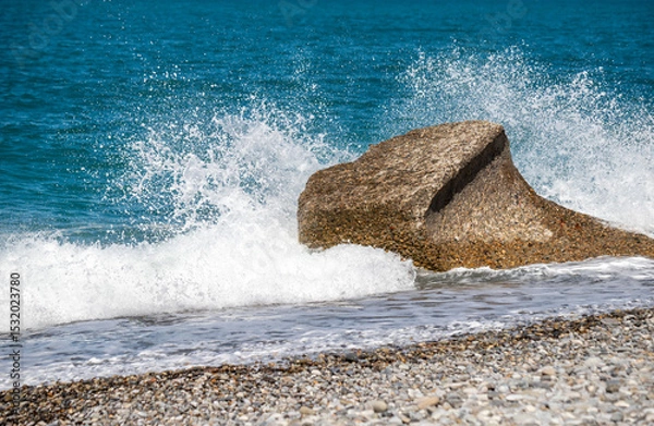 Fototapeta A large rock is in the ocean, and the water is crashing against it