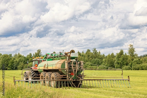 Obraz Tractor fertilizing a field a sunny summer day