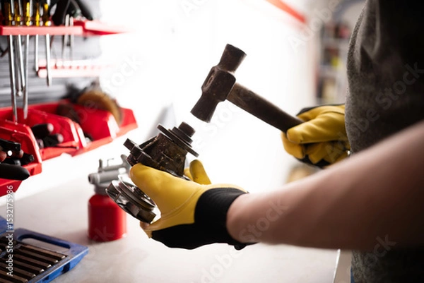Fototapeta Serviceman Repairing Auto Part With Hummer At Workbench