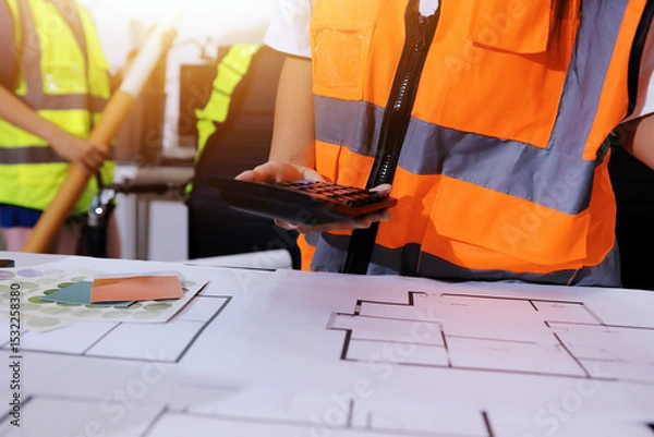 Fototapeta Closeup of team of industrial engineers meeting analyze machinery blueprints consult project on table in manufacturing factory. Working in manufacturing plant or production plant.
