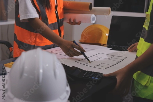 Fototapeta Closeup of team of industrial engineers meeting analyze machinery blueprints consult project on table in manufacturing factory. Working in manufacturing plant or production plant.