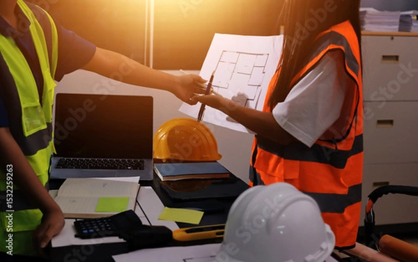 Fototapeta Closeup of team of industrial engineers meeting analyze machinery blueprints consult project on table in manufacturing factory. Working in manufacturing plant or production plant.