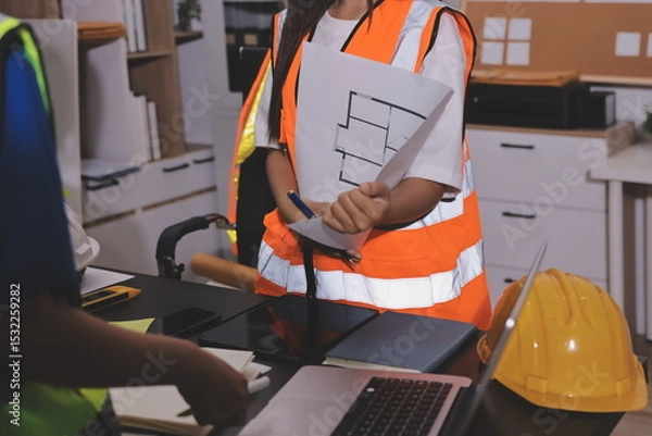 Fototapeta Closeup of team of industrial engineers meeting analyze machinery blueprints consult project on table in manufacturing factory. Working in manufacturing plant or production plant.