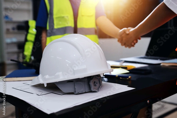 Fototapeta Closeup of team of industrial engineers meeting analyze machinery blueprints consult project on table in manufacturing factory. Working in manufacturing plant or production plant.
