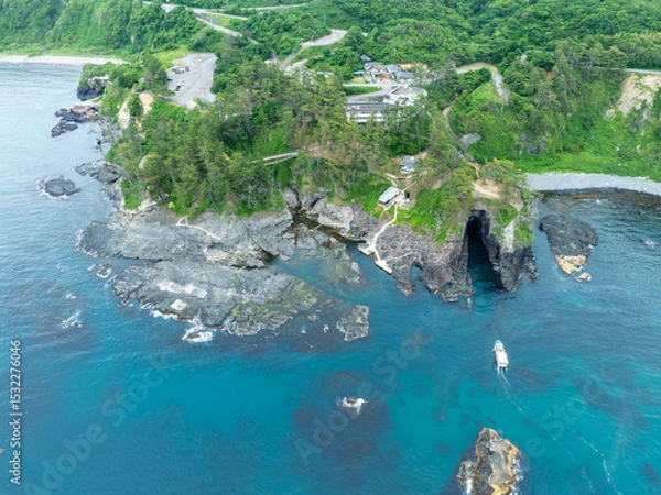 Obraz 巌門の海蝕洞に遊覧船が入っていく様子を上空から撮影した空撮写真。日本海の自然美と観光アクティビティを伝える風景素材。